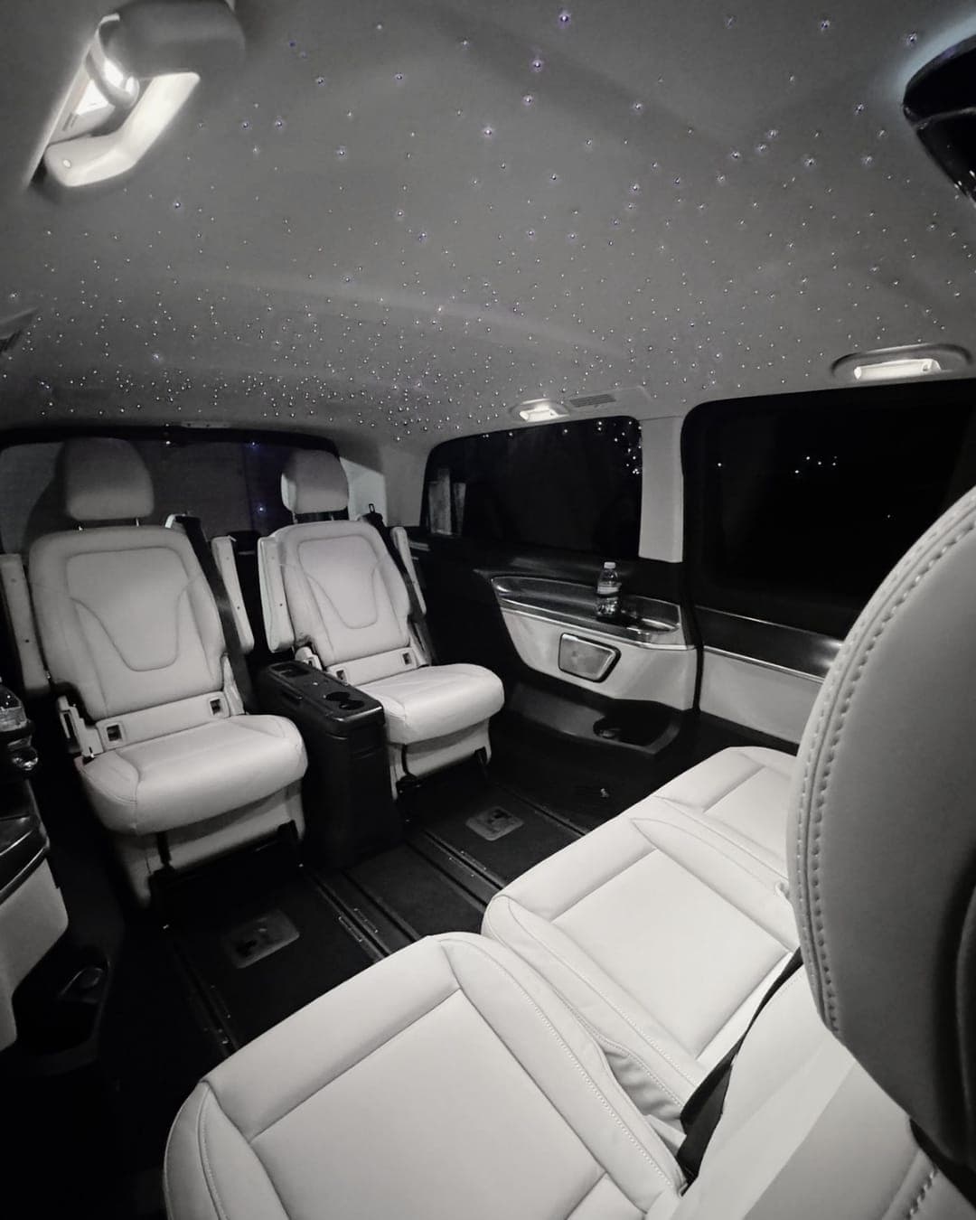 Rear cabin of a Mercedes V-Class with individual white leather seats and a starlight headliner
